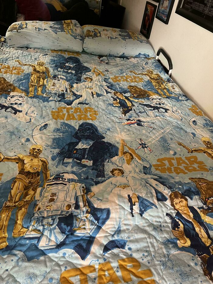 Star Wars themed bedspread with characters from the original movie series on bed