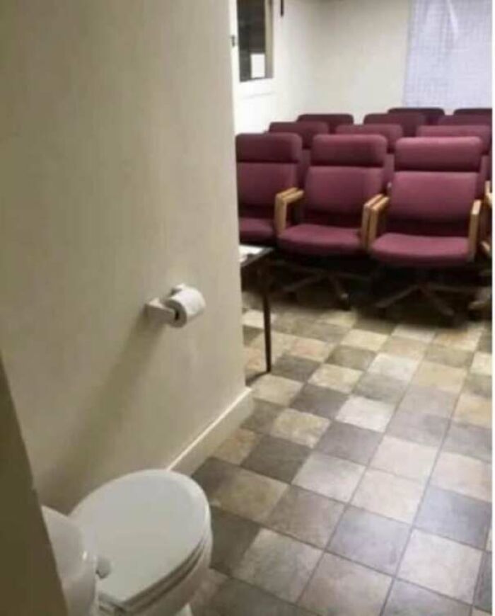 Toilet placed inside a conference room with seating and no privacy