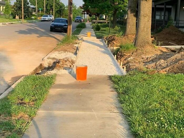 Sidewalk construction fail blocking path with orange bucket on sidewalk