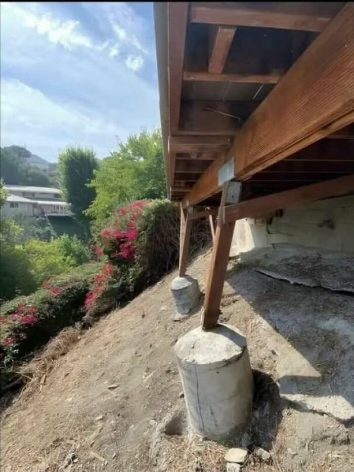 Wooden deck supported on uneven concrete pillars on sloped ground
