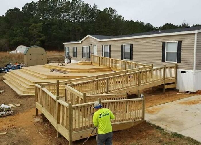 A house with an excessively large and complex wooden deck and ramp system, showing construction fails