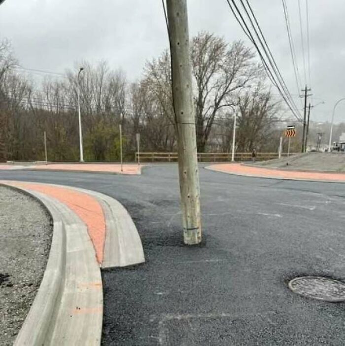 Newly paved road with an awkwardly placed utility pole in the middle