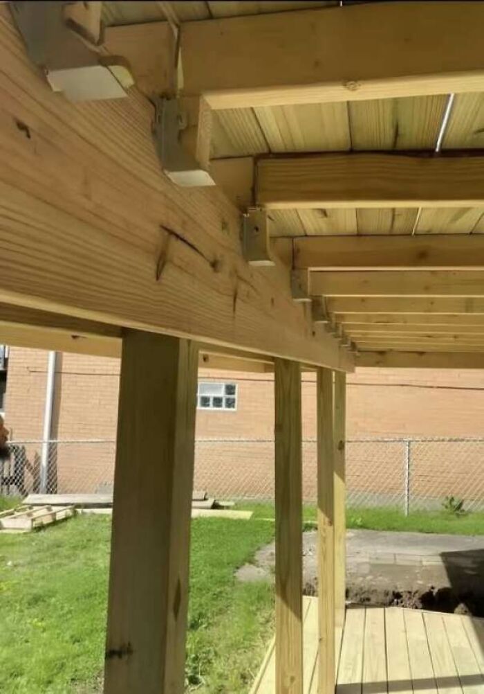 Poorly constructed wooden deck with misaligned support beams and posts