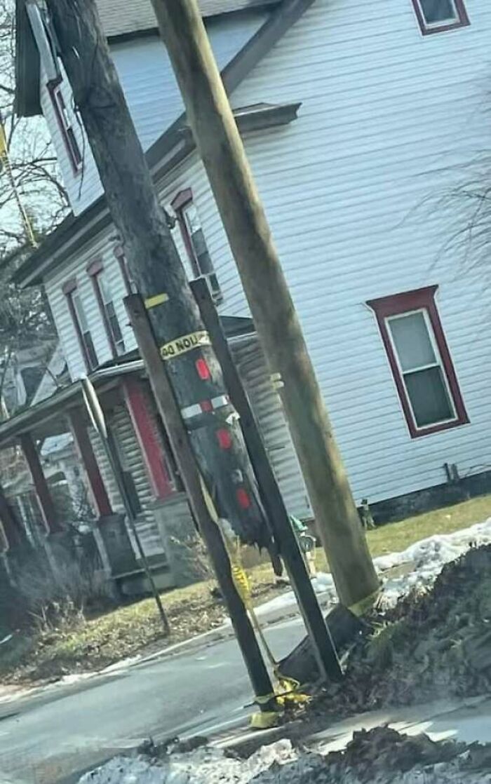 Construction fail showing uneven utility poles poorly secured near a residential street
