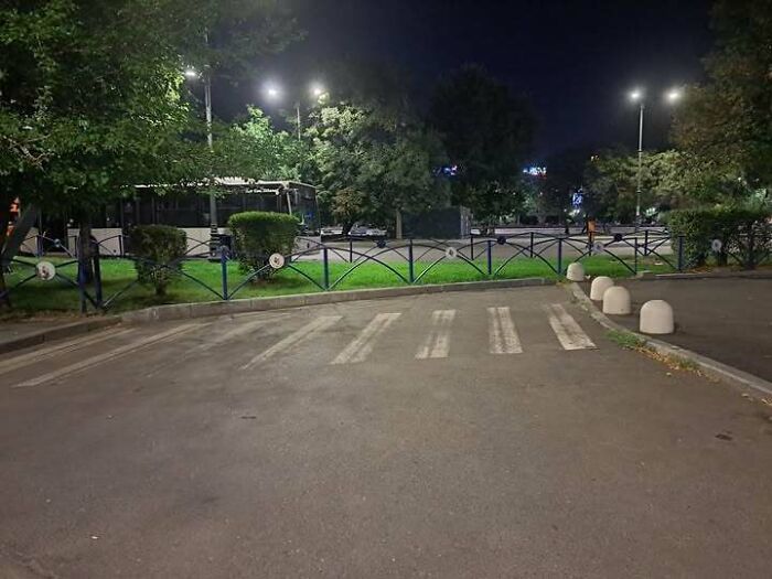 Crosswalk ending abruptly at a fenced grassy area with no path