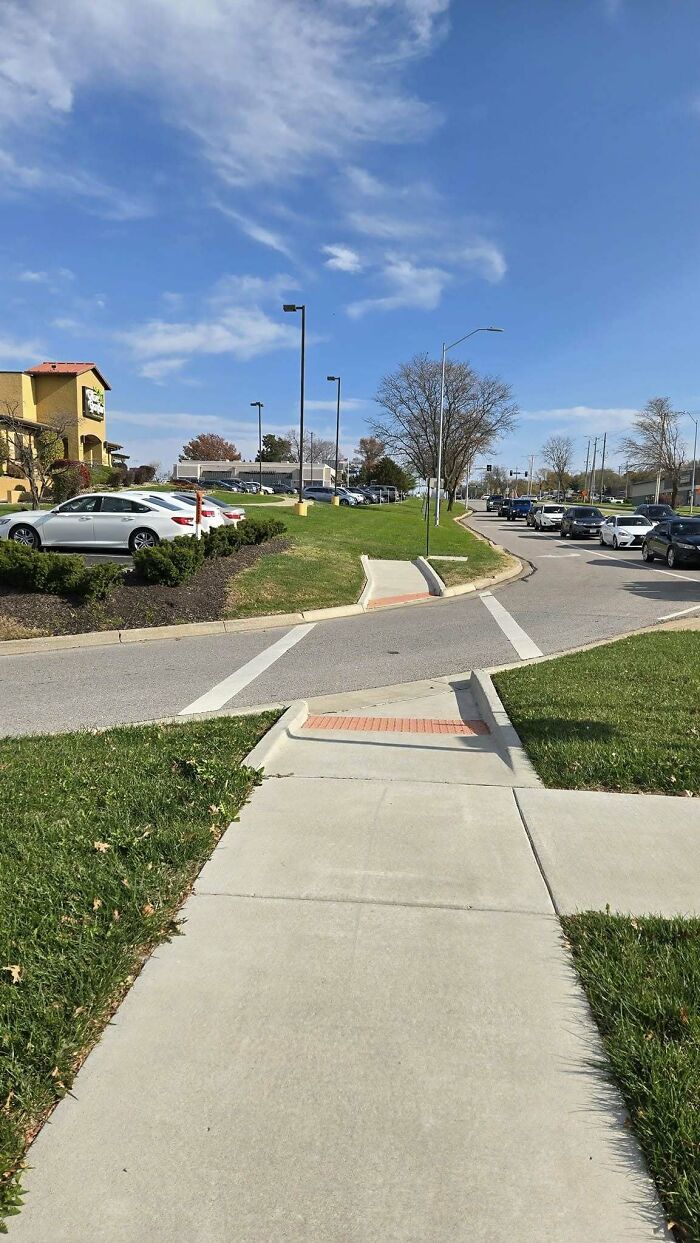 Sidewalk construction fail with impractical pedestrian ramps leading to grass
