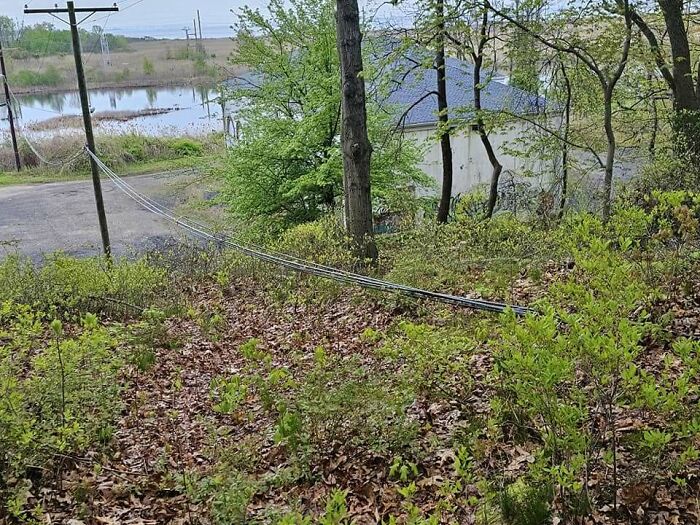 Utility pole cables lying across a grassy hill, an example of poor construction fails.