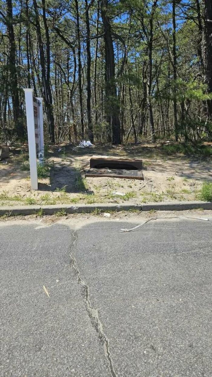 A storm drain placed completely off the road on dirt, showing funny construction fails.
