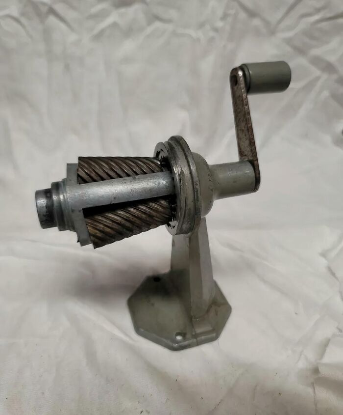 Old-fashioned metal hand-crank meat grinder on white background