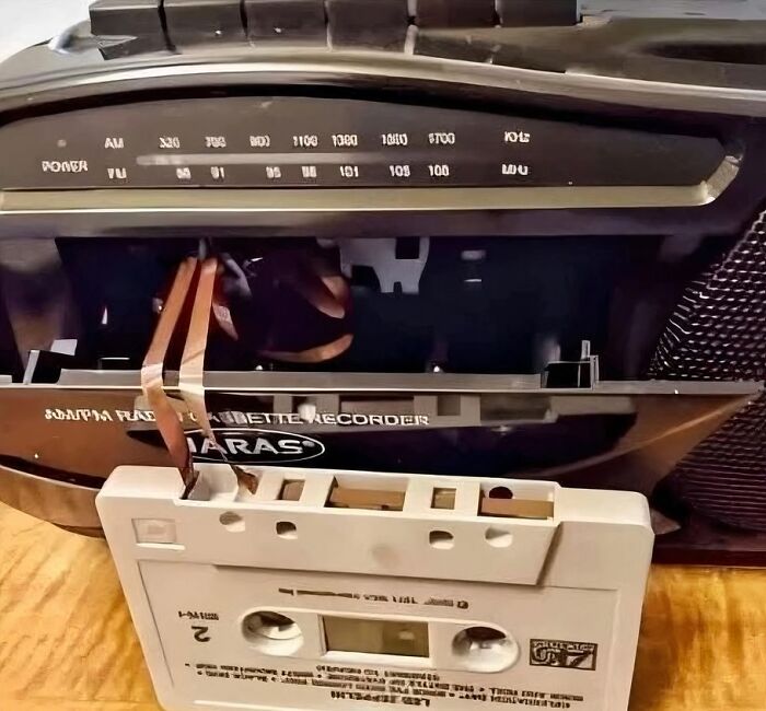 Vintage cassette tape recorder with tape partially pulled out on wooden surface