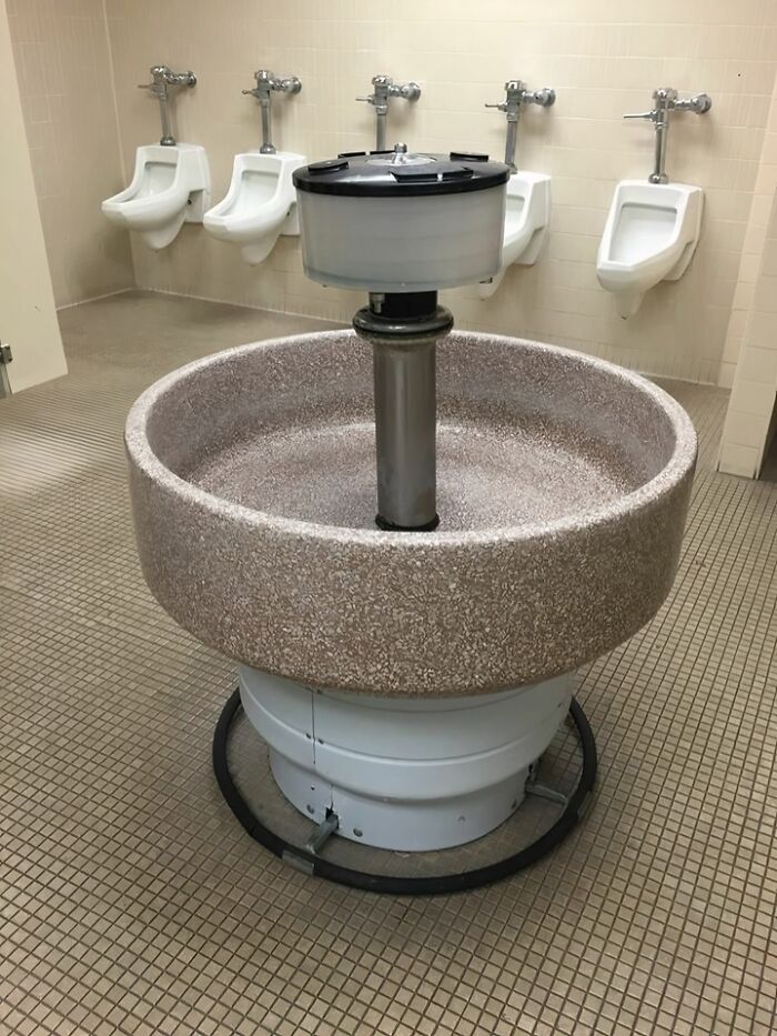 Old public restroom with vintage circular multi-user sink and urinals