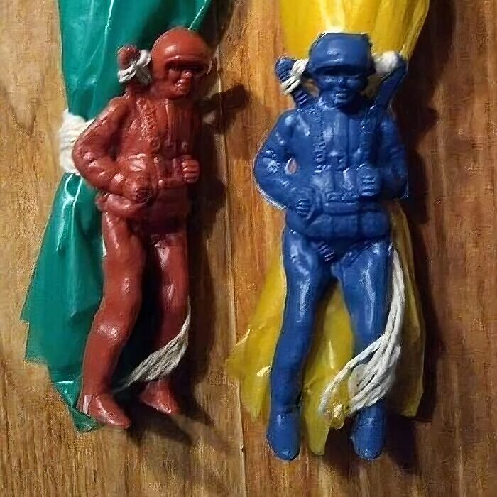 Vintage nostalgic toy paratroopers in red and blue hanging on wooden background