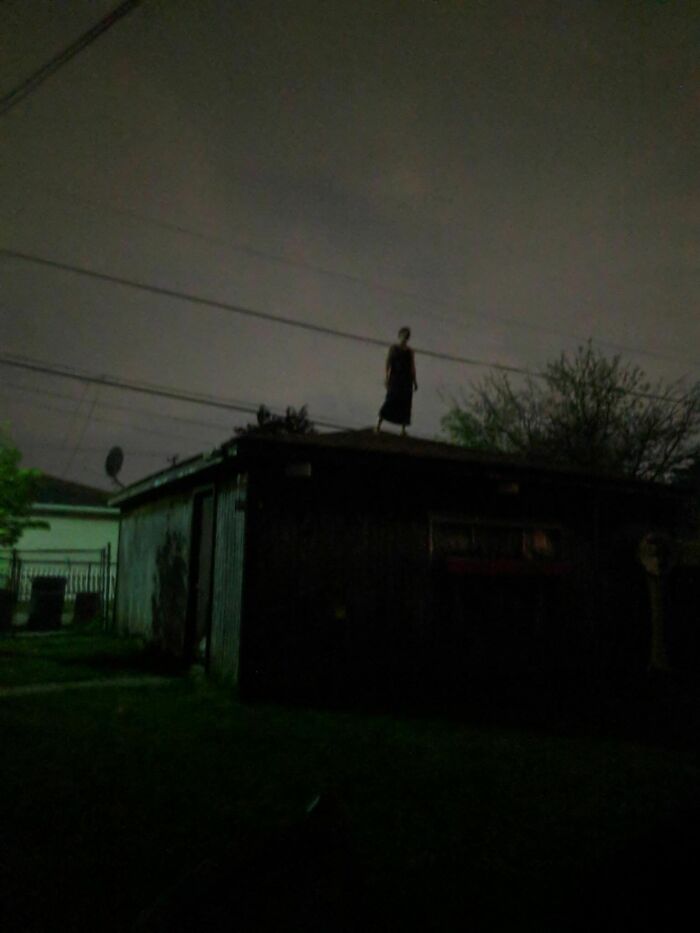A eerie silhouette of a person standing on a roof at night, fitting for cursed images.