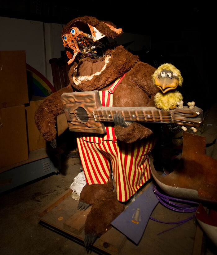 Cursed images showing a broken down animatronic bear holding a guitar in a dark storage room