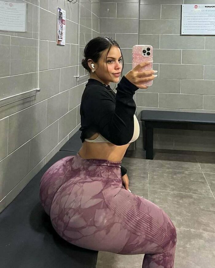 Ridiculously edited gym selfie showing exaggeratedly large hips in workout leggings