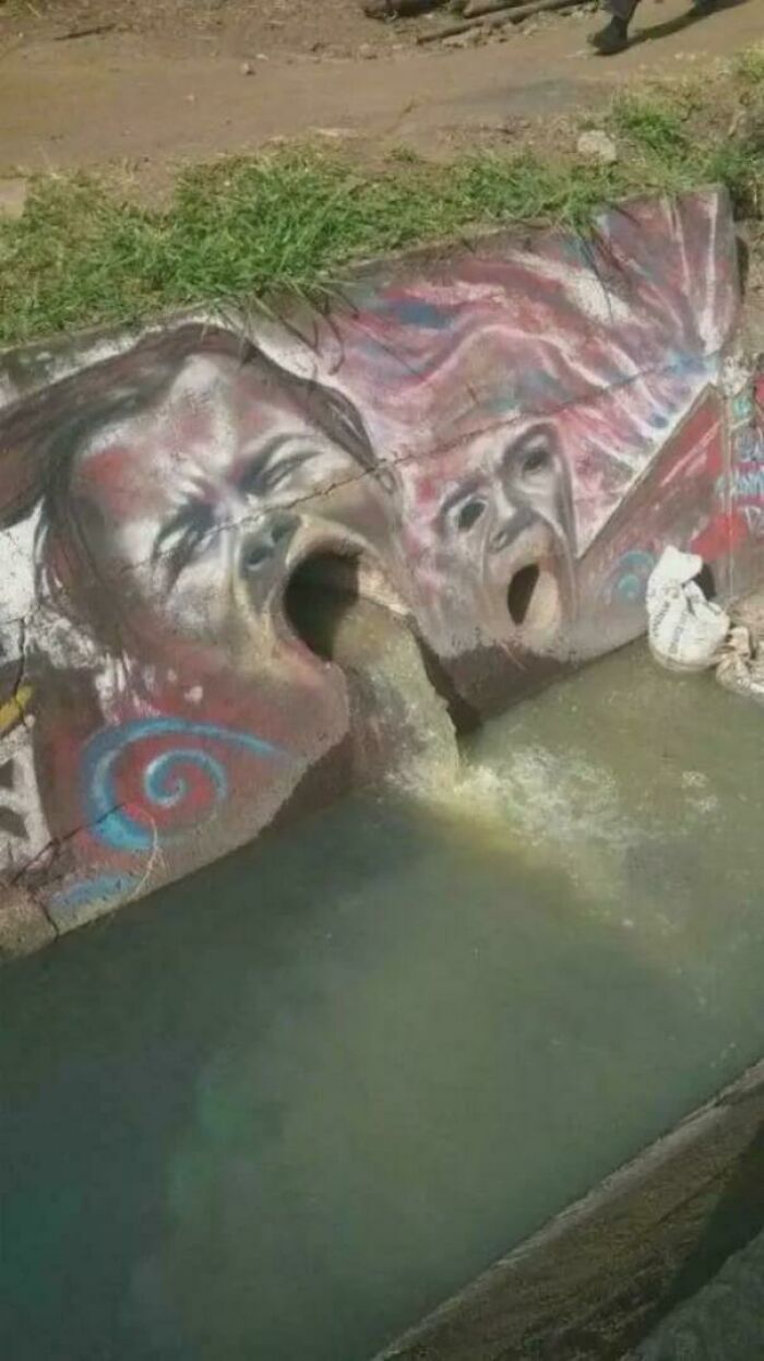 Disturbing graffiti painting of screaming faces spewing water into a canal, an example of cursed images.