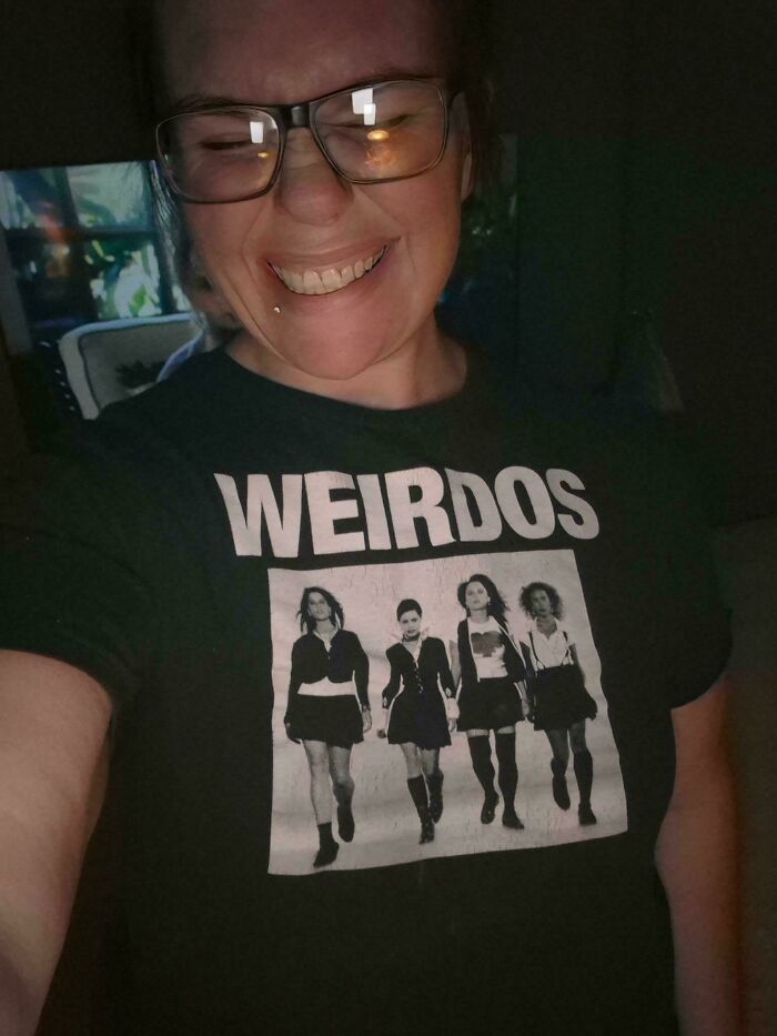 A smiling woman wearing a t-shirt featuring a spooky design, adding to a collection of creepy photos.