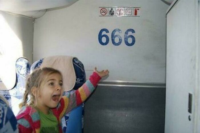 A young girl gesturing excitedly toward the number 666 printed on a wall, capturing a moment among cursed images.