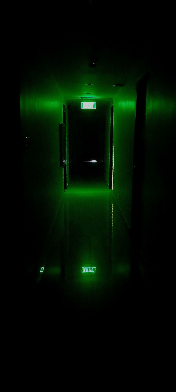 A glowing green illuminated dark hallway giving off a vibe of cursed images.