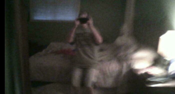 Creepy photos captured on a phone showing a shadowy blurred figure taking a photo in a dim bedroom.