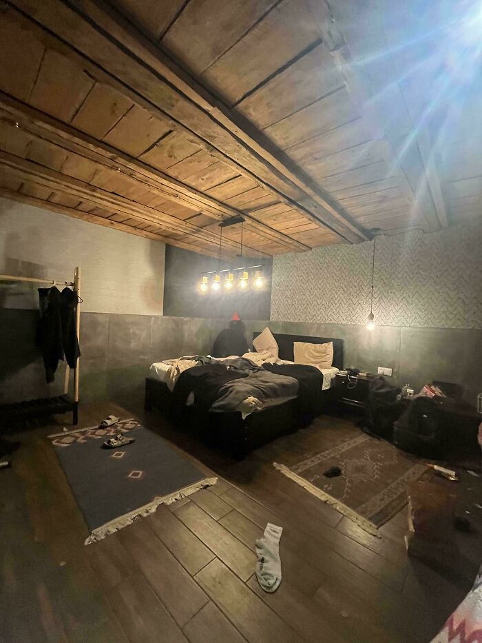 A dimly lit bedroom with a shadowy figure behind the bed, exemplifying creepy photos.