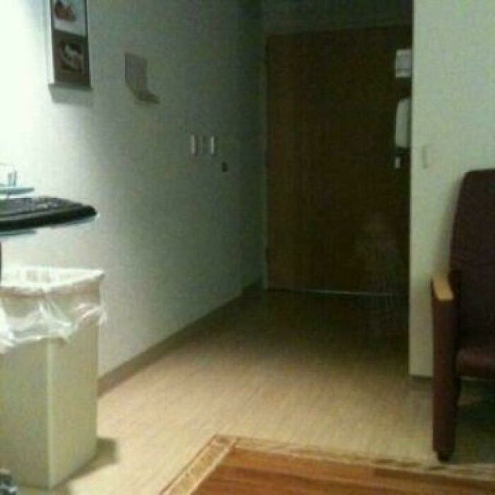 One of many creepy photos depicting a dark hallway in a hospital with a faint shadow near a door