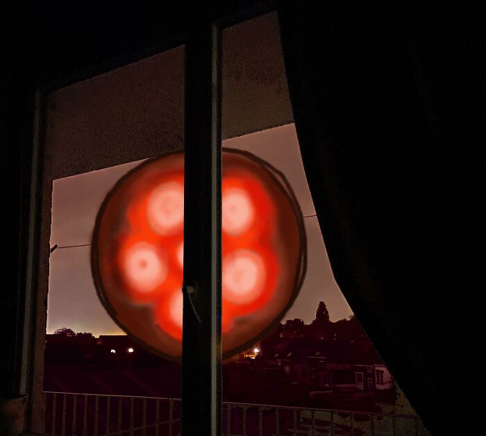 Glowing red orb seen through a window night view as featured in creepy photos