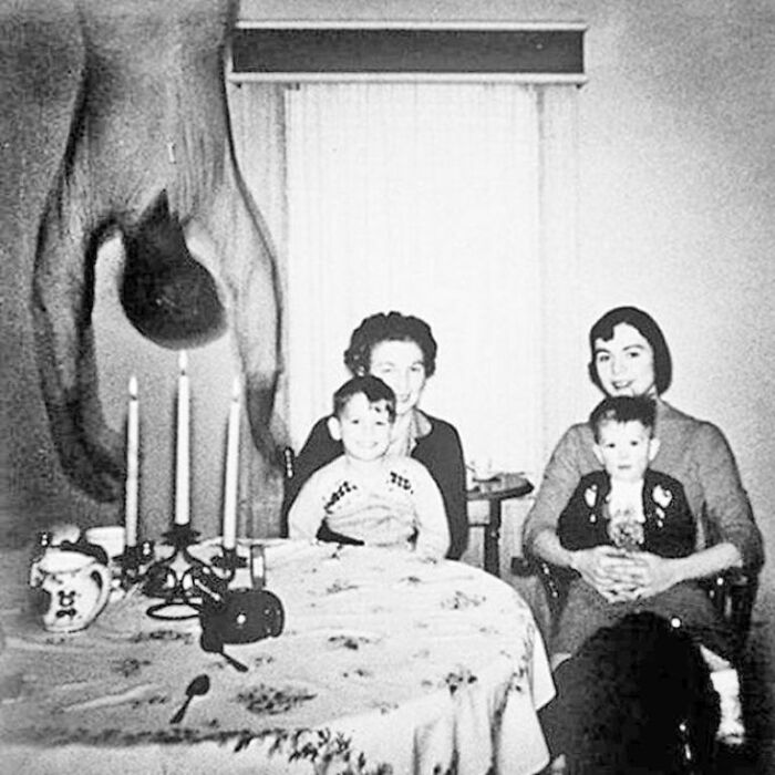 Vintage family photo showing creepy photos of inverted figure hanging over table.