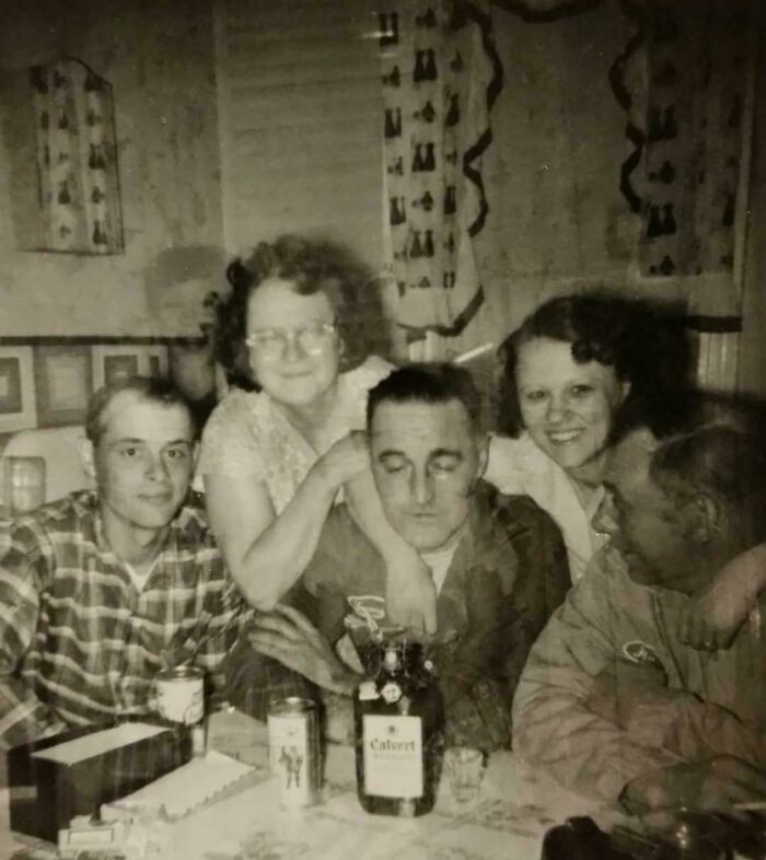 A vintage group portrait showing a faint shadowy face in the background, among creepy photos with mysterious lore.