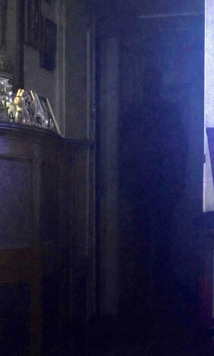 A shadowy figure standing in a dark doorway, one of many creepy photos with no clear explanation.