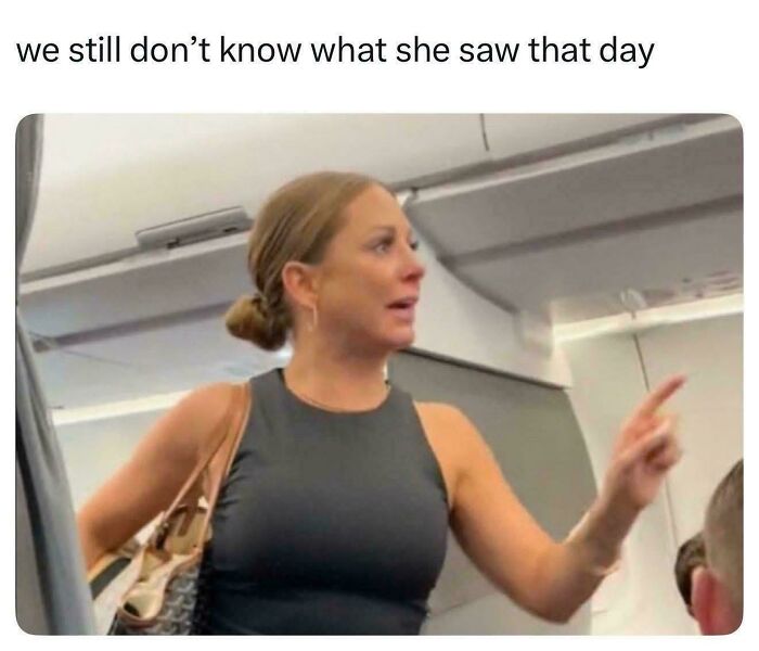Woman in sleeveless black top pointing inside plane puzzled