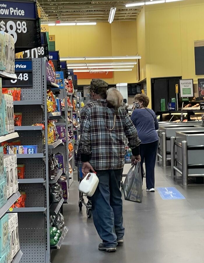 Person carrying milk and bags in Walmart grocery aisle