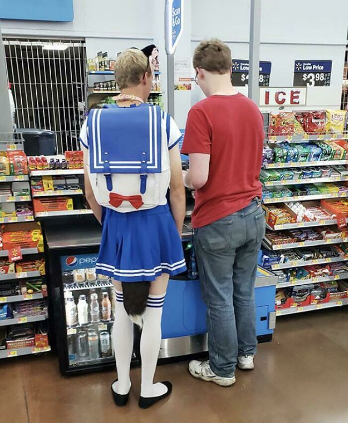 Person in blue sailor-style outfit with tail and another person at Walmart checkout