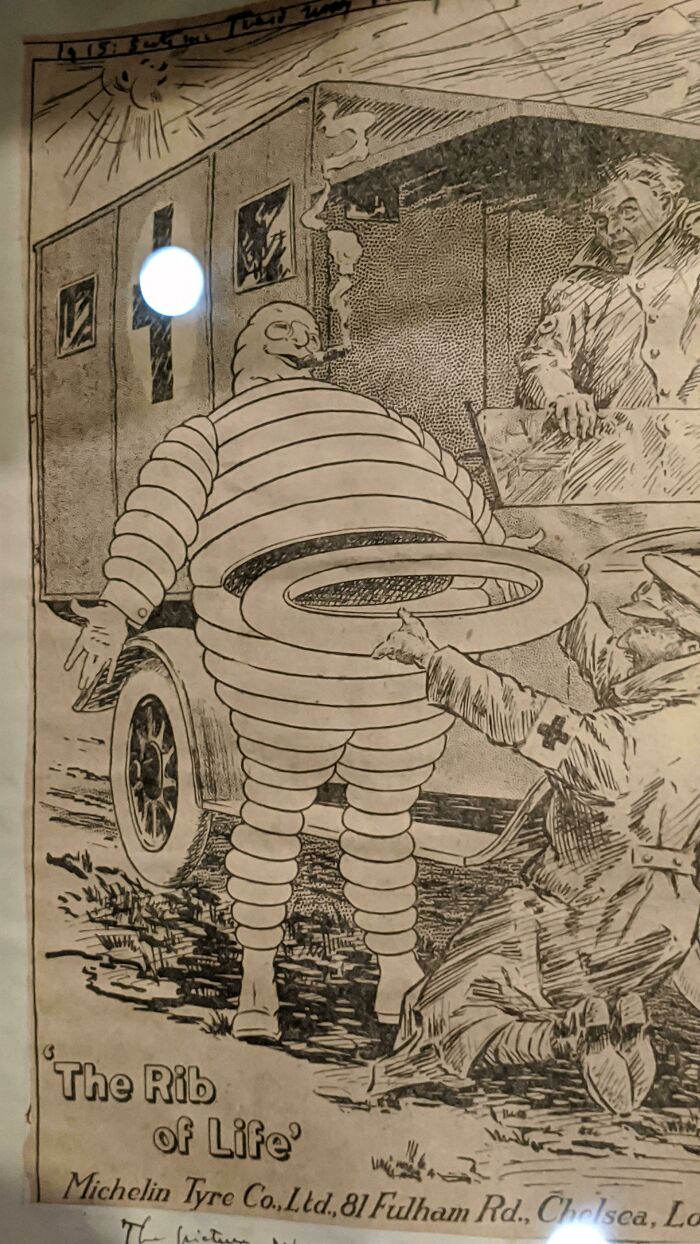 Historical cartoon showing Michelin Man sculpture with the rib of life tire theme