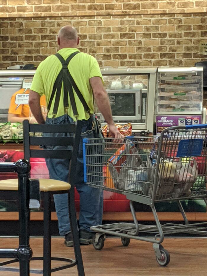 Man in bright yellow shirt pushing shopping cart at Walmart checkout