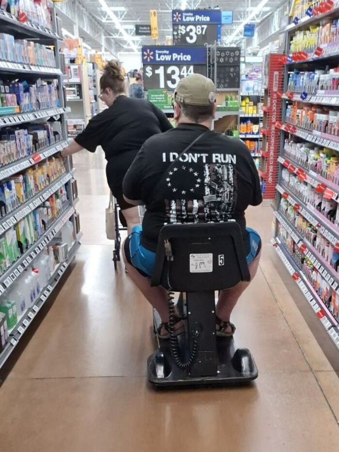 Person riding motorized scooter with low price signs in Walmart aisle