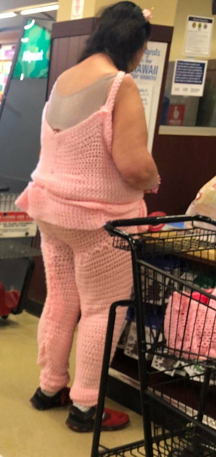 Woman wearing pink crochet outfit shopping at Walmart with cart nearby