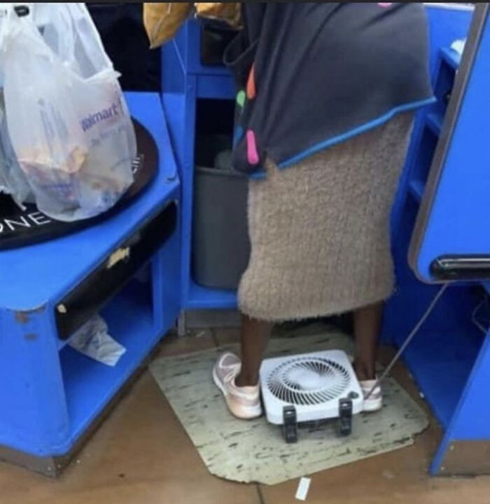 Woman standing at Walmart checkout with small fan under feet