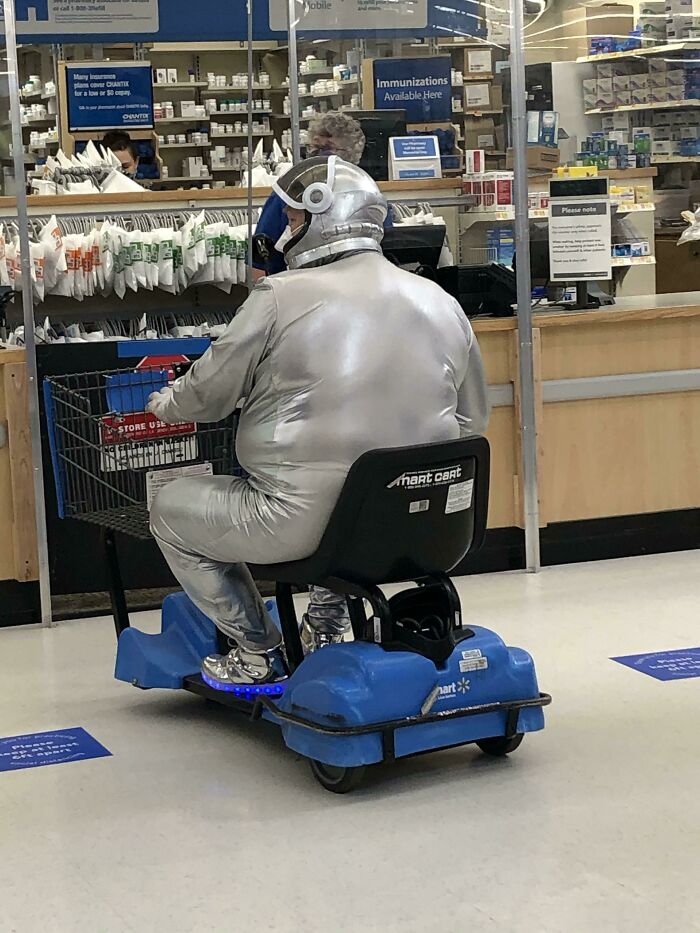 Person dressed in silver astronaut suit riding Walmart mobility scooter