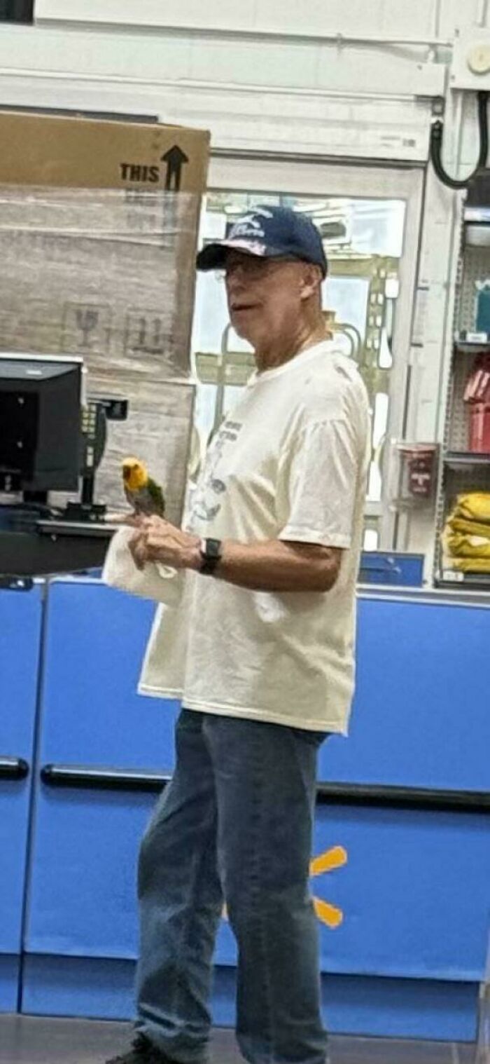 Man holding a colorful bird inside a Walmart store near checkout counters