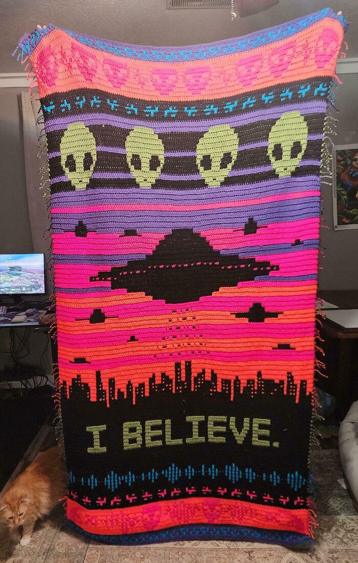 Colorful crochet blanket with aliens, UFO, and cityscape with I believe text