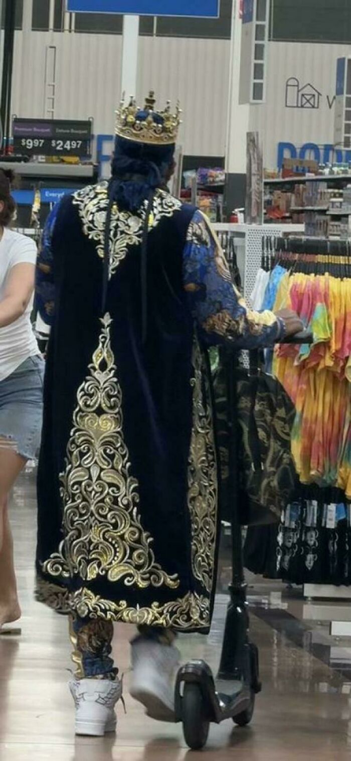 Person dressed in ornate royal costume riding scooter inside Walmart