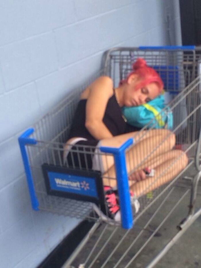 Young woman sleeping curled up inside Walmart shopping cart