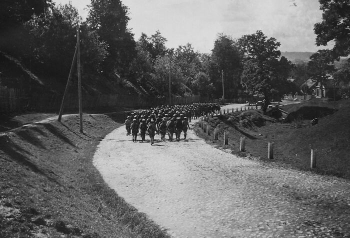 Historical photo of soldiers marching on rural road with trees
