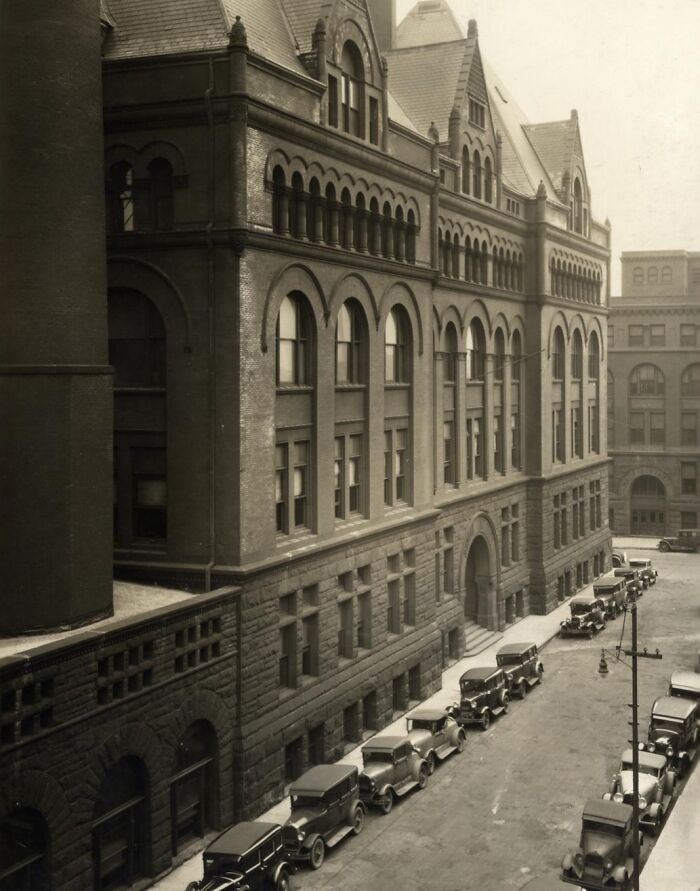 Rare historical street view photo of early 20th century cars parked alongside a large brick building