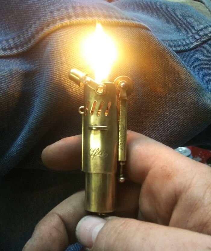 Vintage rare historical photo of a hand holding a lit antique brass lighter