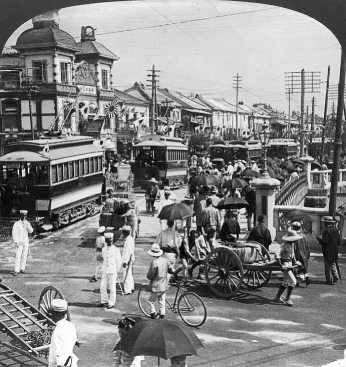 Historical photo showing busy city street with trams and pedestrians