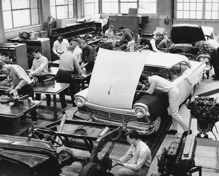 Vintage car workshop with mechanics working on vehicles