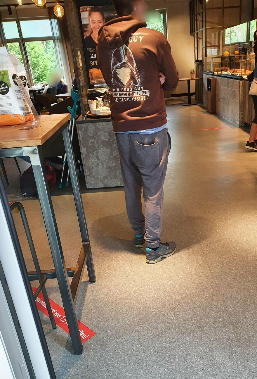 Man wearing hoodie with tough guy graphic standing in cafe