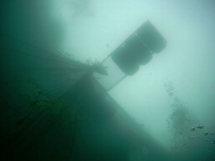 Deep water view of a submerged structure and floating debris underwater